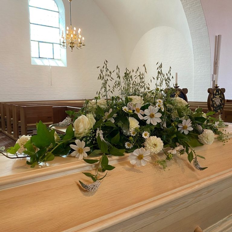 Kistepynt med hvide blomster på en kiste i kirken