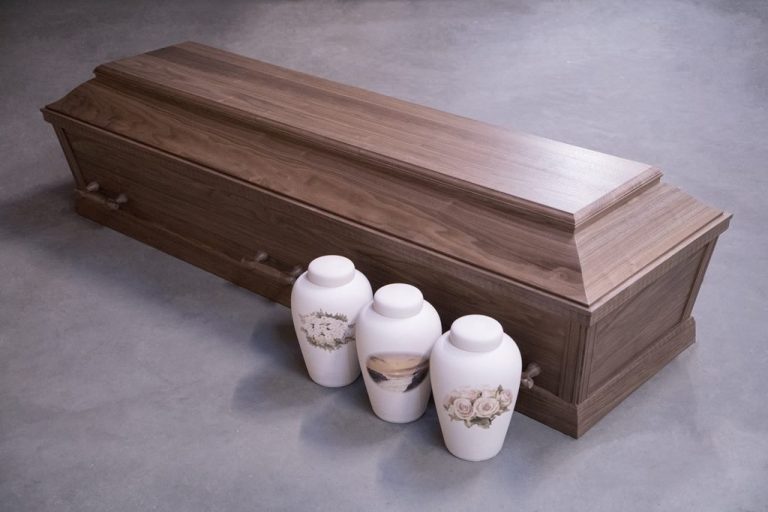 Mørk kiste med tre hvide urner